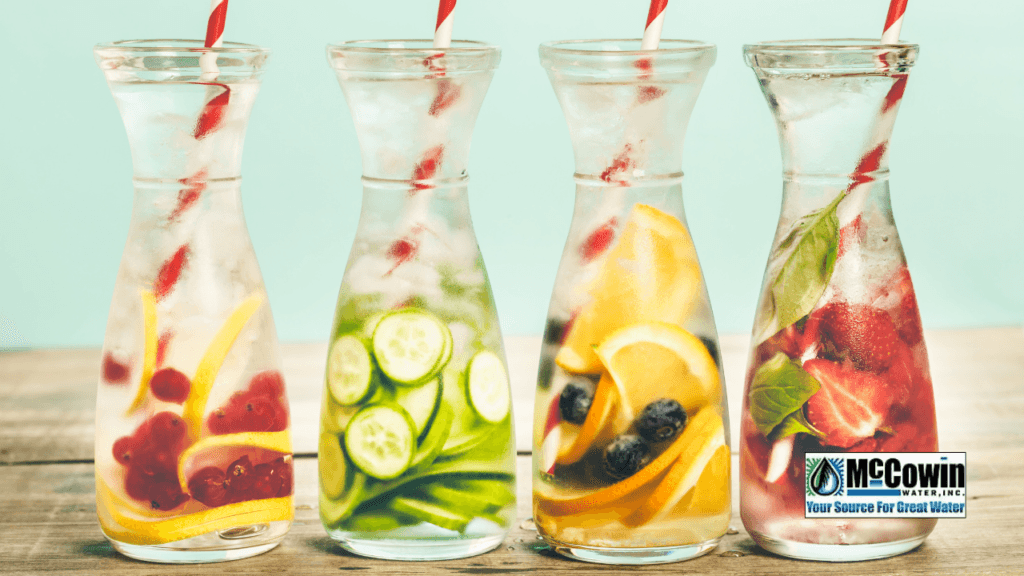 Four glass carafes of fruit-infused water, symbolizing clean, filtered drinking water made possible by full home water filtration systems from McCowin Water.