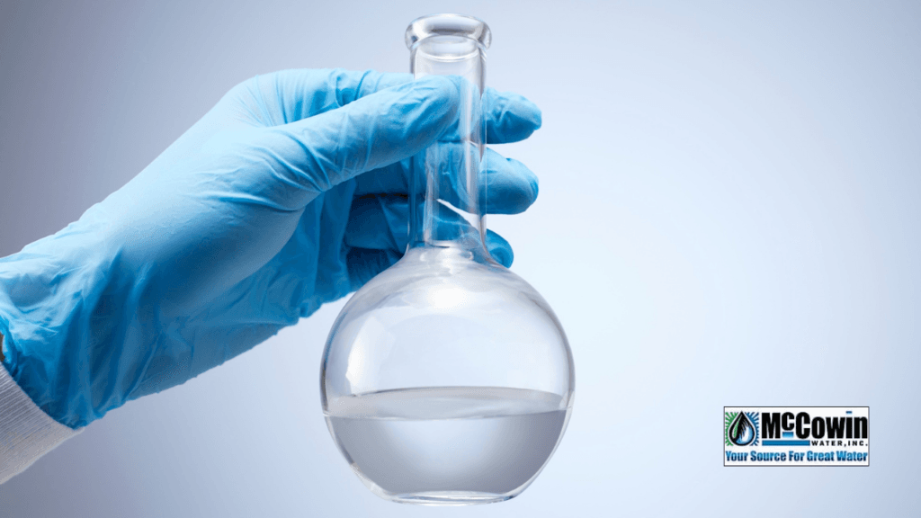 Water Hardness Test Strip: What It Really Tells You (And What It Doesn’t) Gloved hand holding a glass flask of clear water, representing professional testing that goes beyond a simple water hardness test strip.