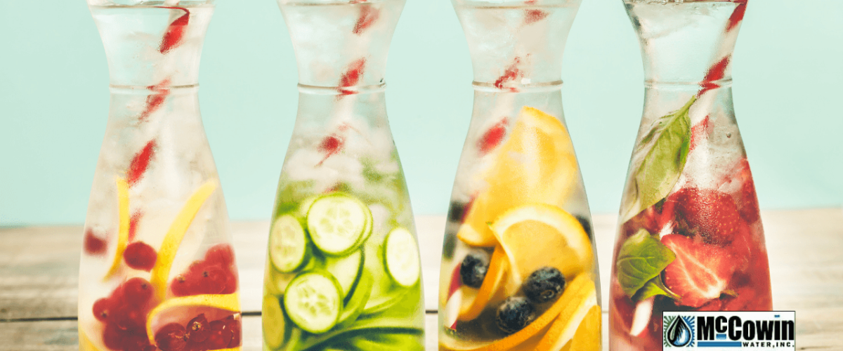 Four glass carafes of fruit-infused water, symbolizing clean, filtered drinking water made possible by full home water filtration systems from McCowin Water.