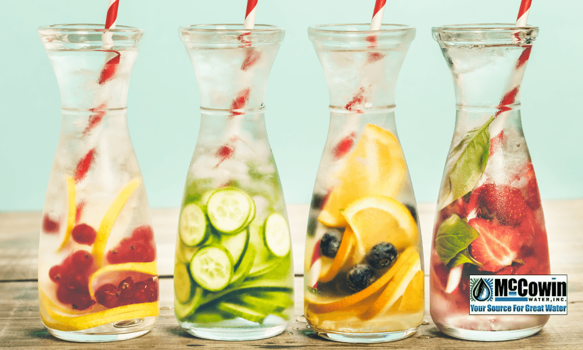 Four glass carafes of fruit-infused water, symbolizing clean, filtered drinking water made possible by full home water filtration systems from McCowin Water.